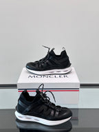 Moncler black lace-up sneaker with sculpted sole and side logo detail; box visible.