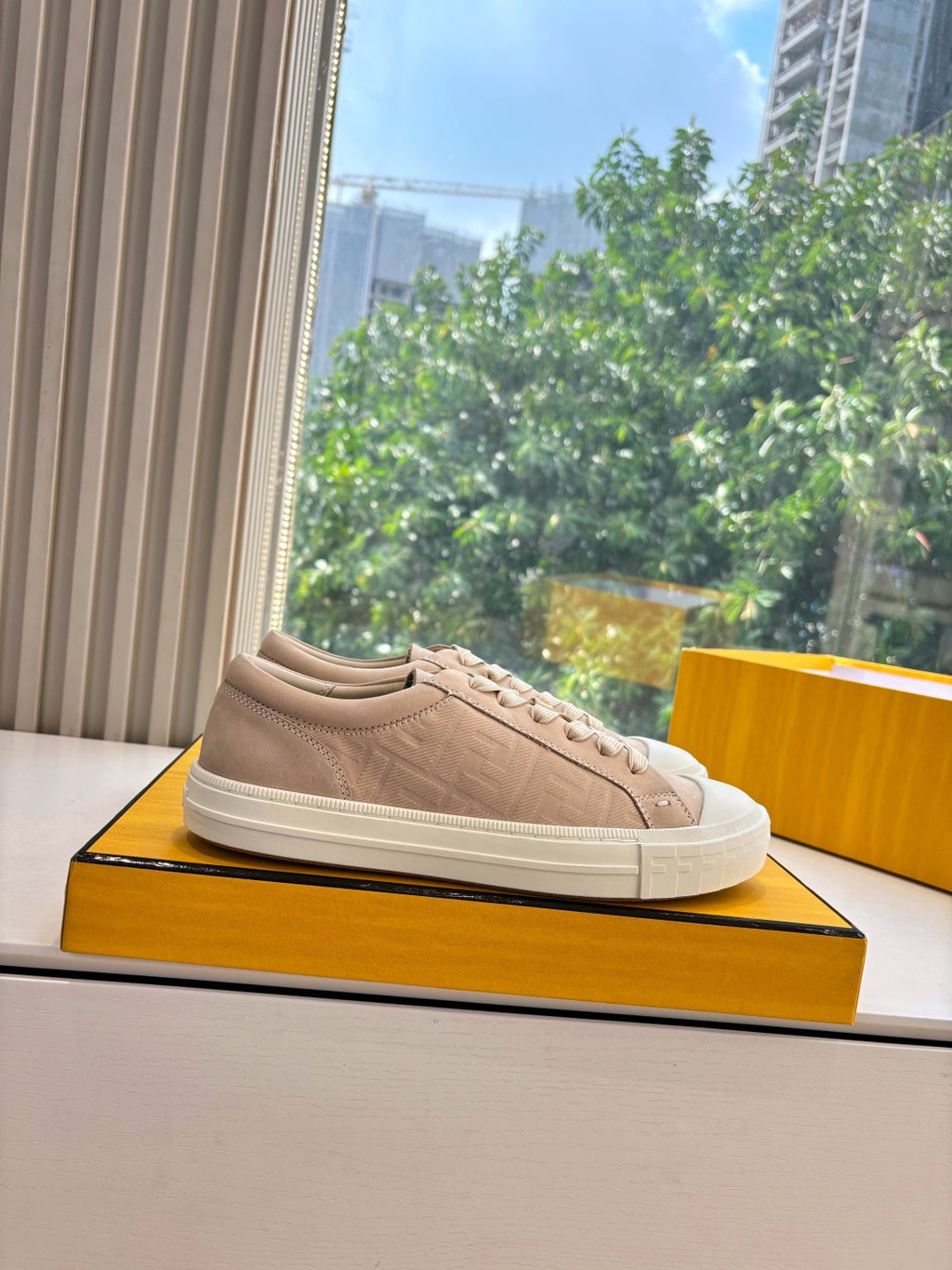 Beige low-top sneaker with textured panels and lace-up closure, on display.