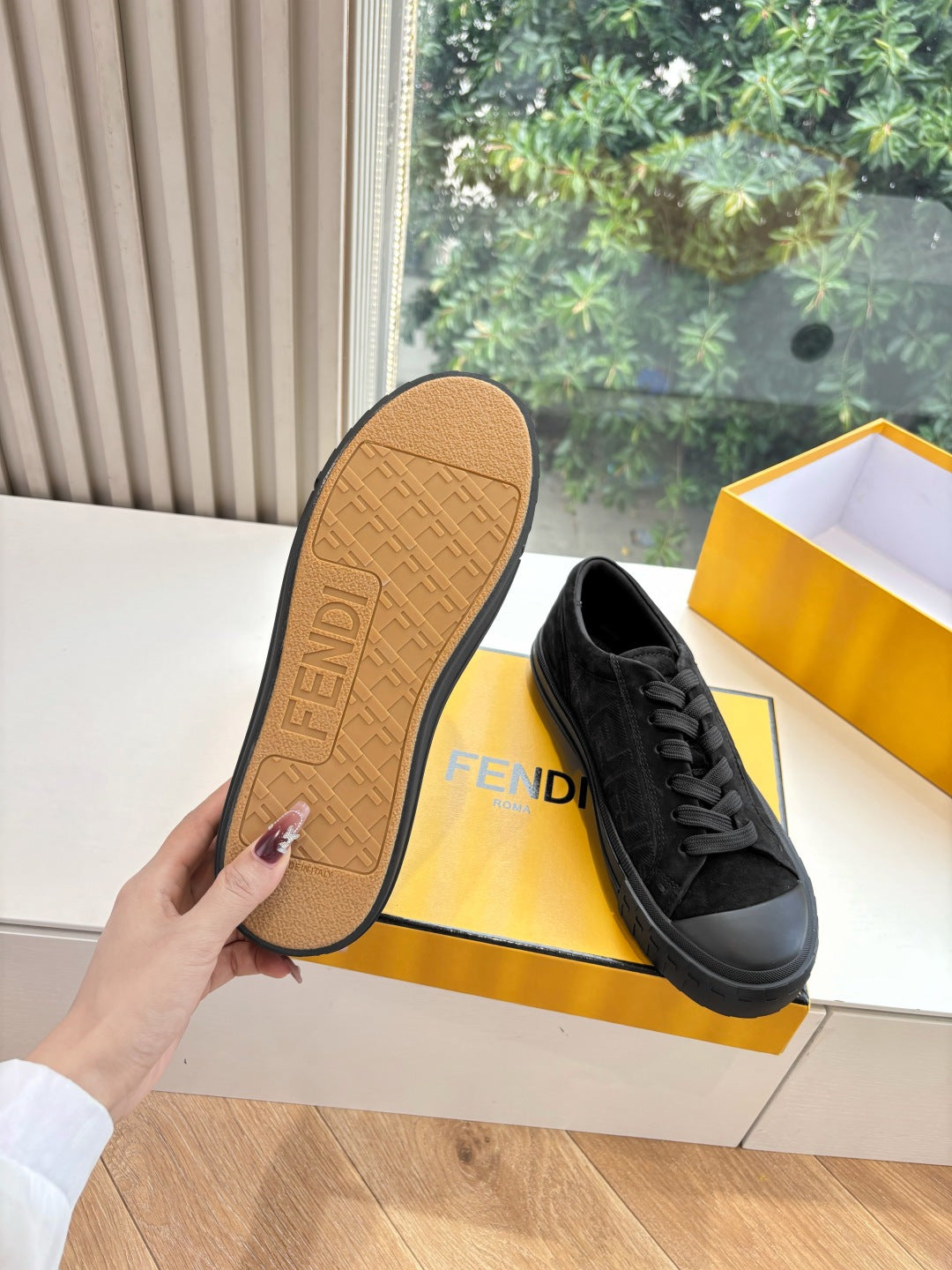Black Fendi sneakers showing tan outsole underside with logo tread pattern