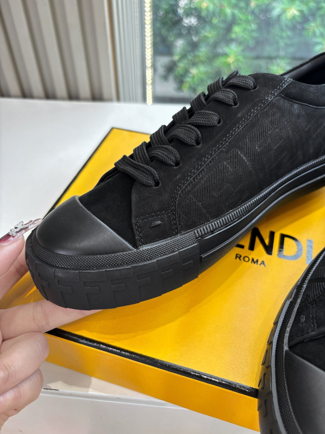 Black Fendi sneaker close-up with lace-up top and embossed side pattern