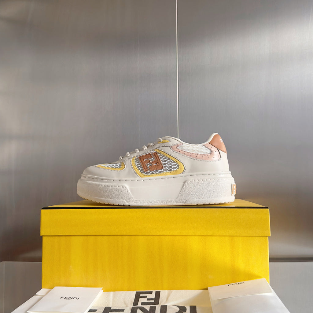 White unisex sneakers with brown, yellow, and pink emblem patch on the side