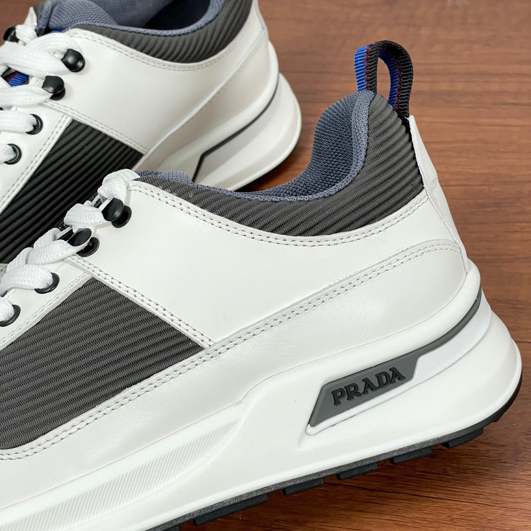 Prada unisex sneakers side detail, white trim, dark gray fabric, PRADA badge