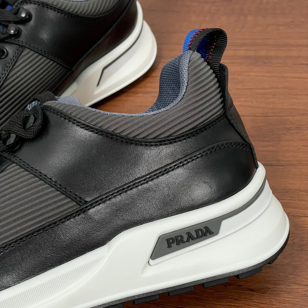 Prada sneakers side detail, PRADA logo plaque on black and gray upper with white sole