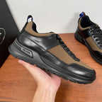 Prada unisex sneakers held by hand, black leather with tan side panel and logo