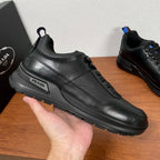 Prada unisex side view sneaker held in hand, black leather with PRADA logo plate