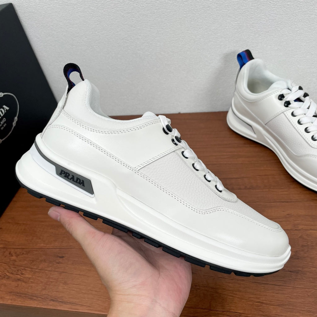 Prada unisex sneaker side view, white leather with PRADA logo and blue-red heel tab
