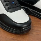 Prada unisex sneaker toe and side view, black laces, white leather panel, textured sole edge