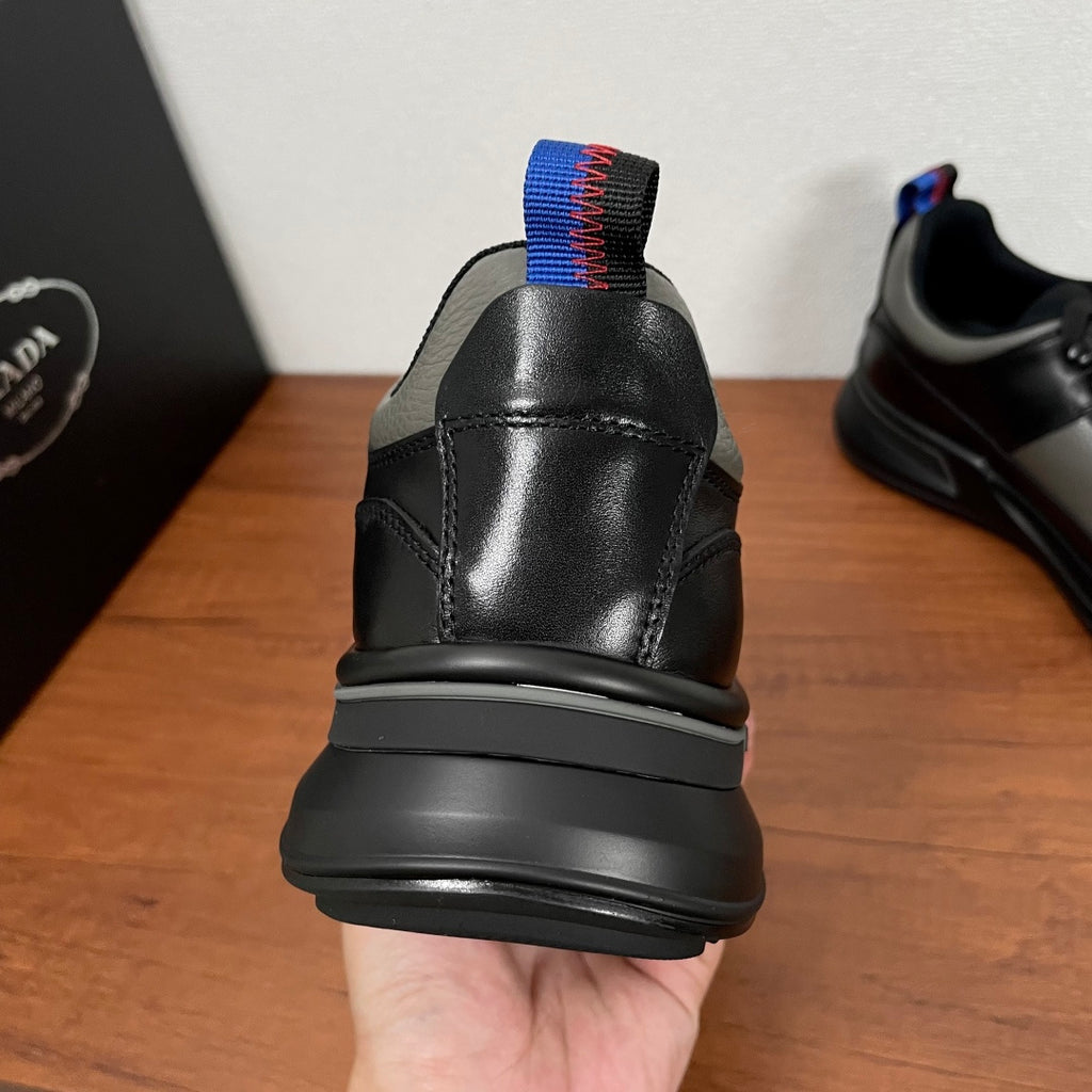 Prada unisex sneaker heel view, black leather with blue and red knit pull tab