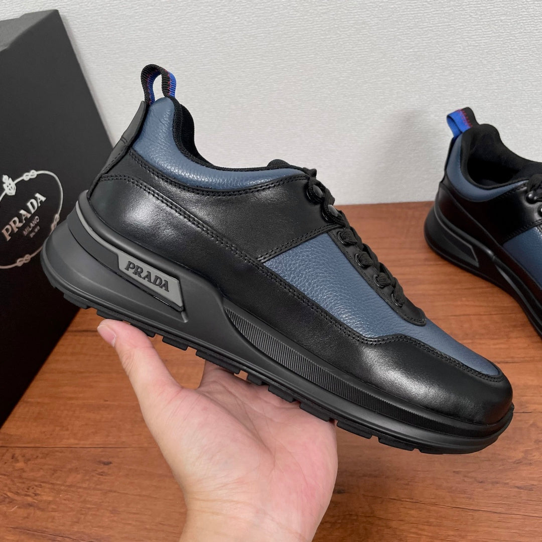 Prada unisex sneaker on hand, black/blue leather upper with PRADA side logo