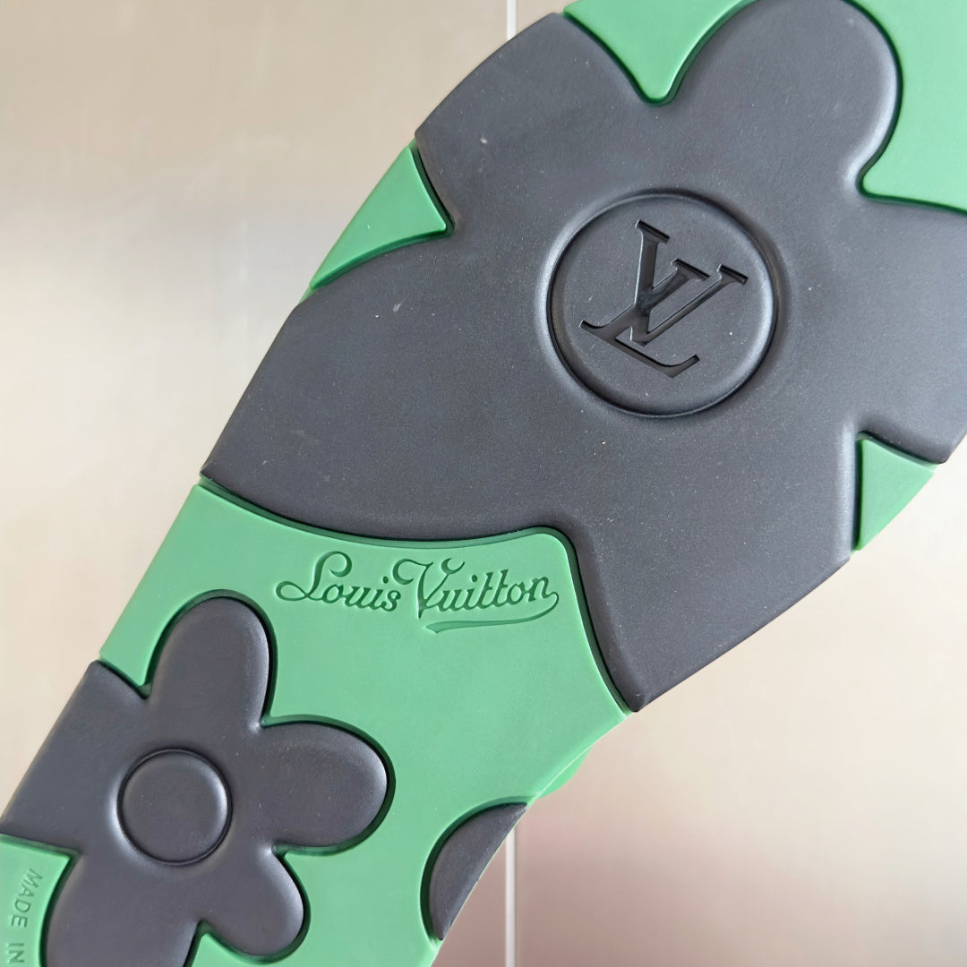 Louis Vuitton sandal close-up showing black base, mint strap, and “Louis Vuitton” emboss