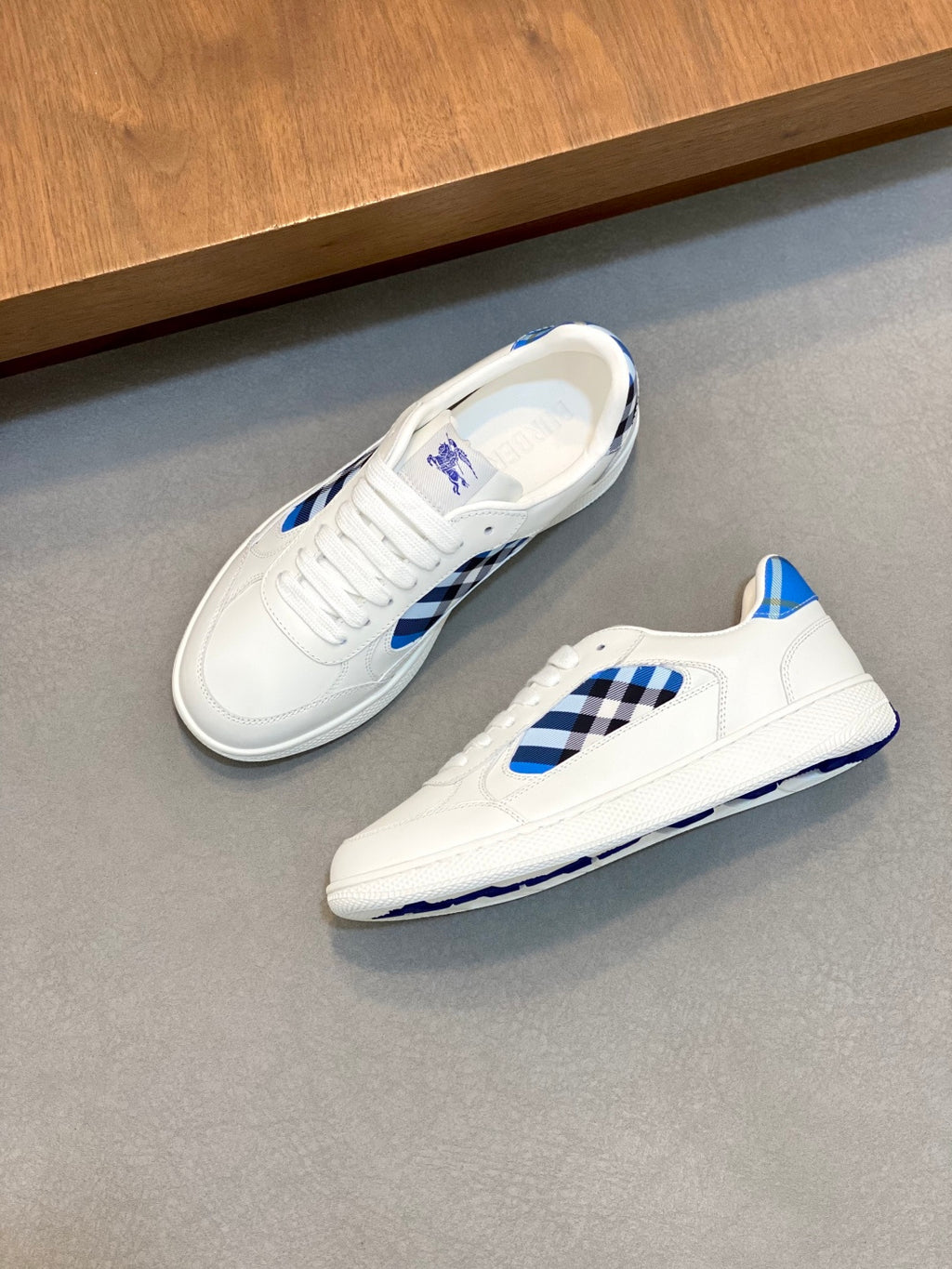 White low-top sneaker with blue check side panel and blue heel accent