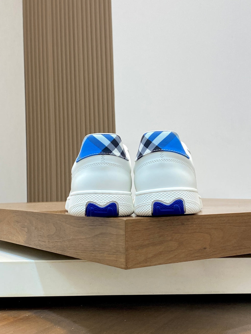 Pair of white sneakers showing blue heel tabs and check-style upper panels