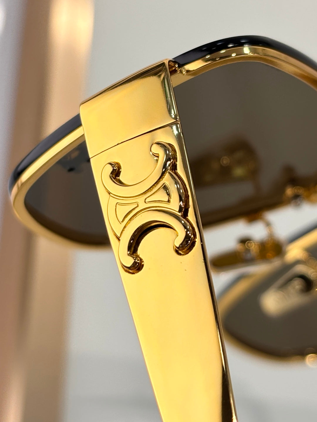 Celine sunglasses close-up of gold temple with embossed logo on tinted lens frame