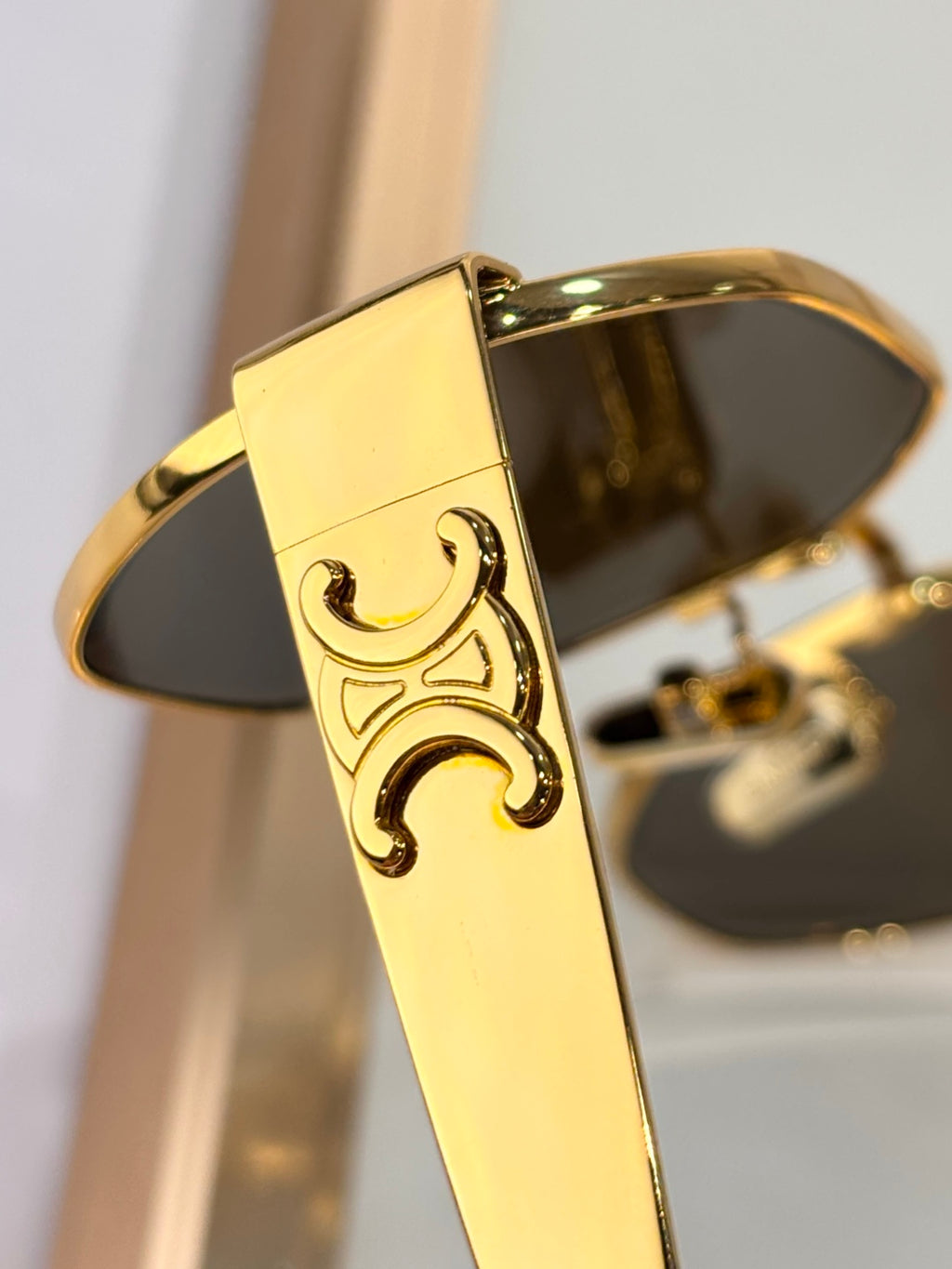 Celine sunglasses close-up: ornate gold temple detail and dark tinted lens