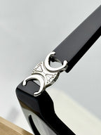Close-up of black eyeglasses temple tip with silver C emblem at the end