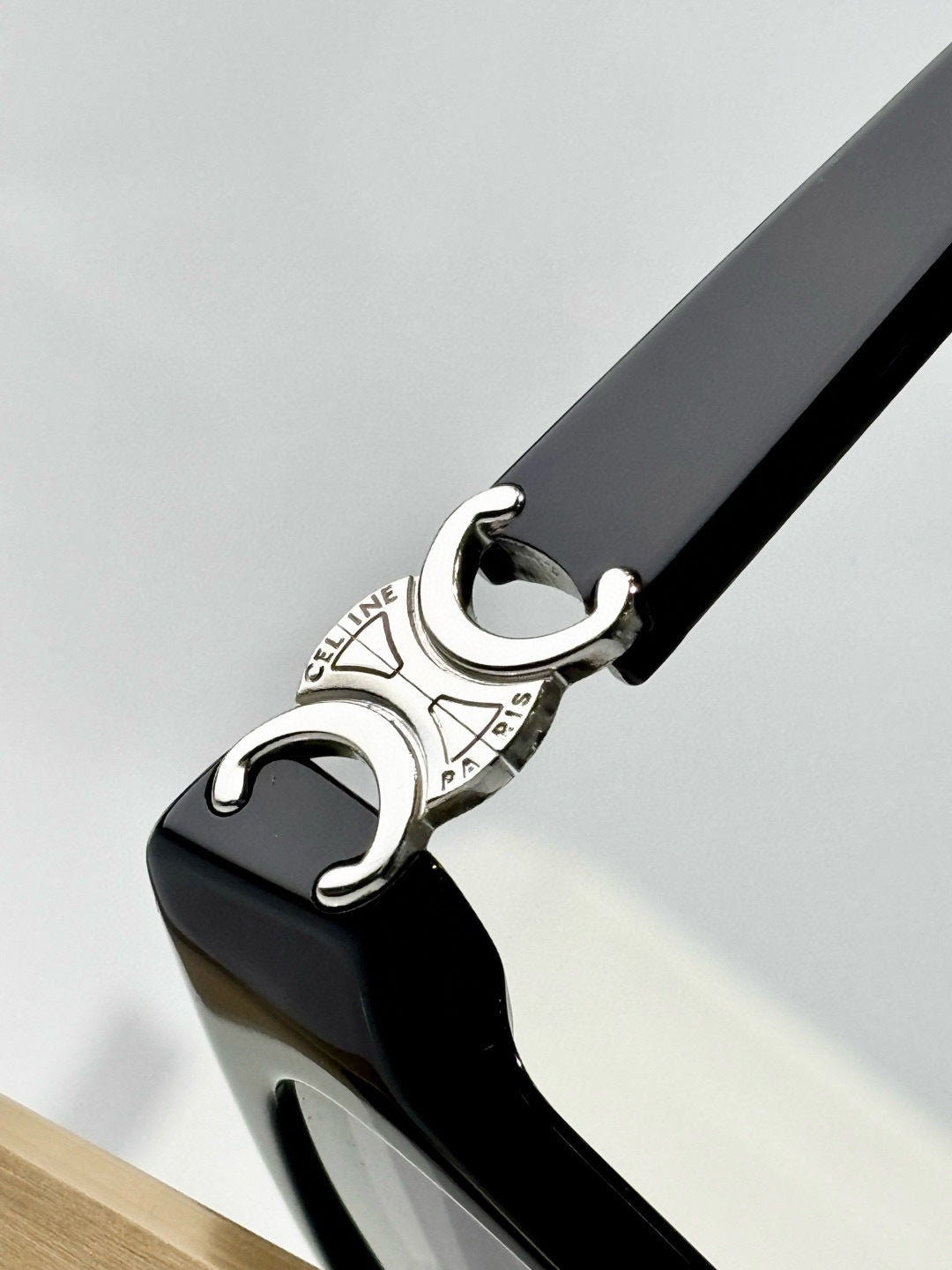 Close-up of black eyeglasses temple tip with silver C emblem at the end