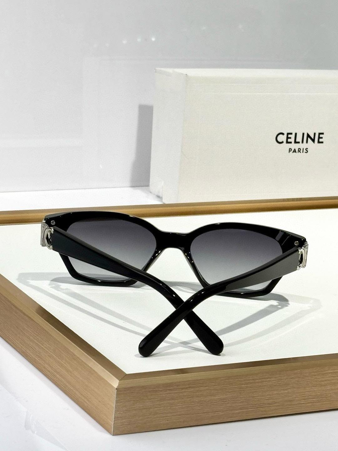 Black cat-eye sunglasses with dark lenses and slim gold metal bridge