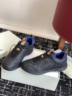 Black low-top sneakers with blue interior and tan lace-tab accents, angled view