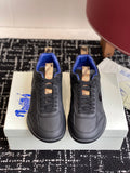Black low-top sneakers with blue interior, tan lace-tab accents and rubber sole