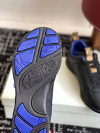 Sneaker outsole with blue tread pattern on black rubber sole, sole view