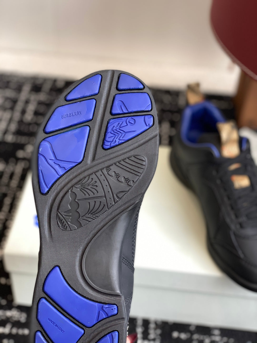 Sneaker outsole with blue tread pattern on black rubber sole, sole view
