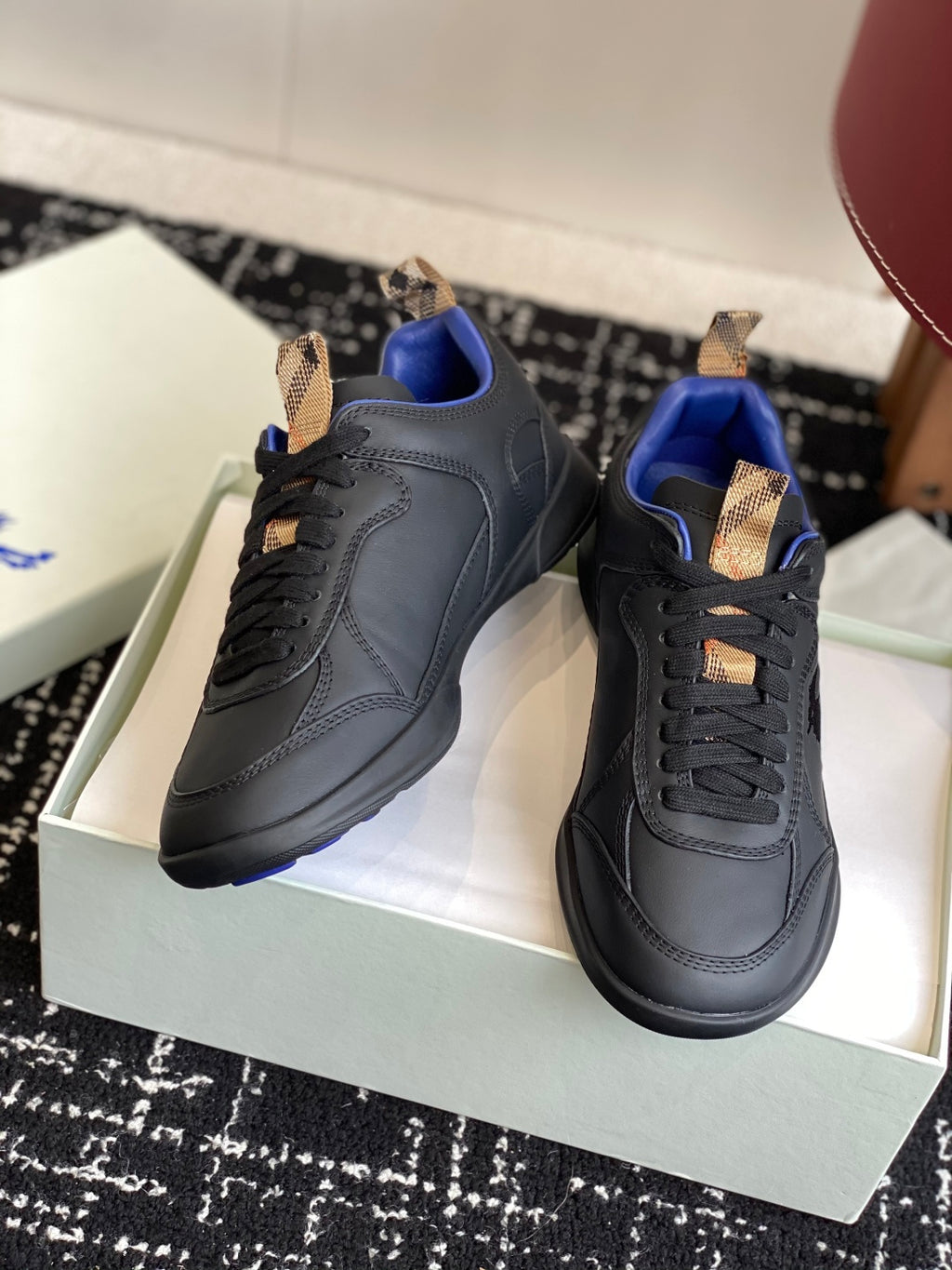 Black low-top sneakers with blue interior and tan lace-tab accents, side/front view