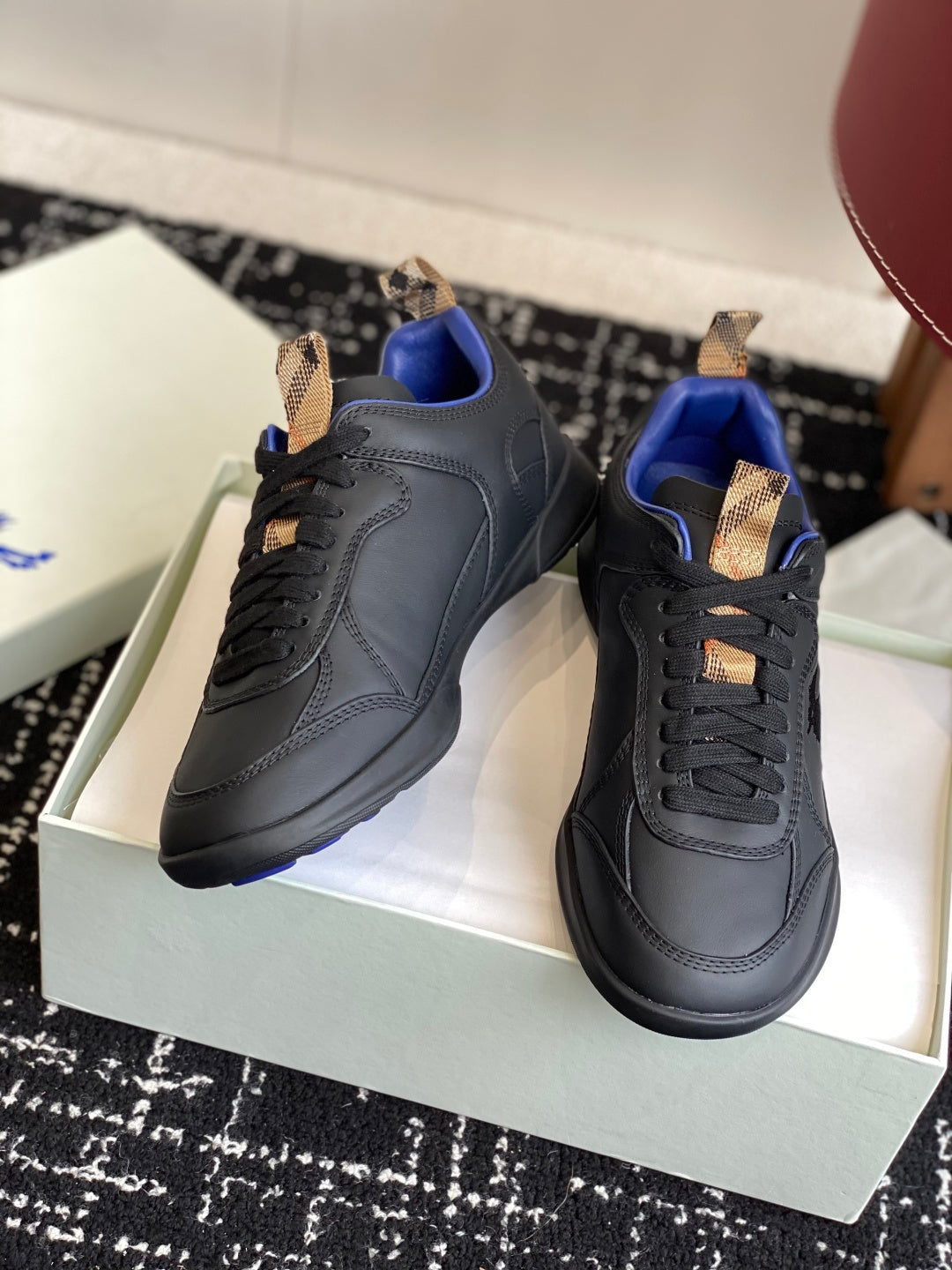 Black low-top sneakers with blue interior and tan lace-tab accents, side/front view