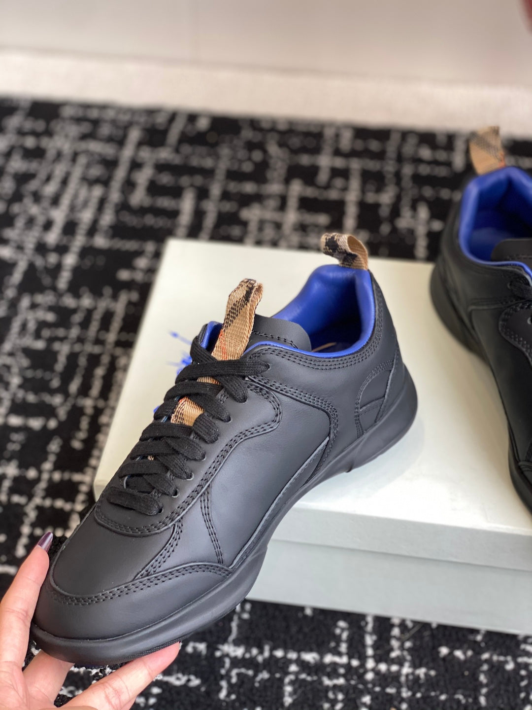 Black low-top sneaker with blue lining, tan lace-tab detail, close side view