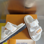 White monogram slide sandals with tan logo patch and visible black side sole edge