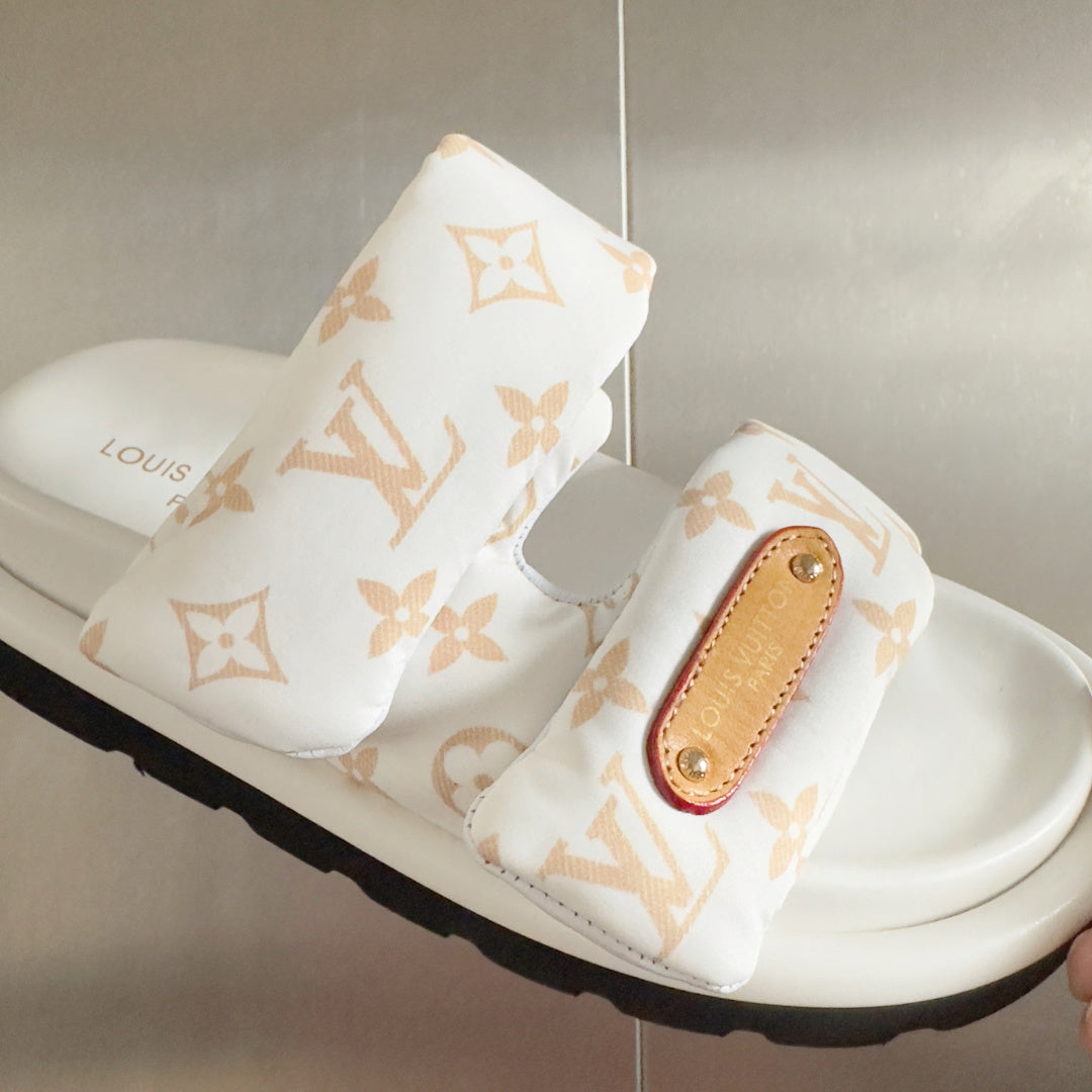 White monogram slide sandal with tan leather logo patch on front strap