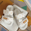 White monogram slide sandals with tan leather logo patch and contoured footbed