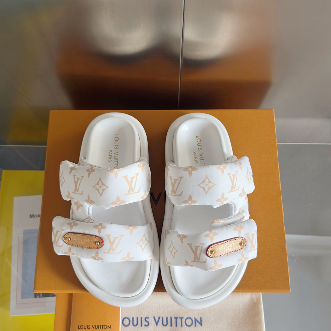 Front view pair of white monogram slide sandals with tan leather logo patch