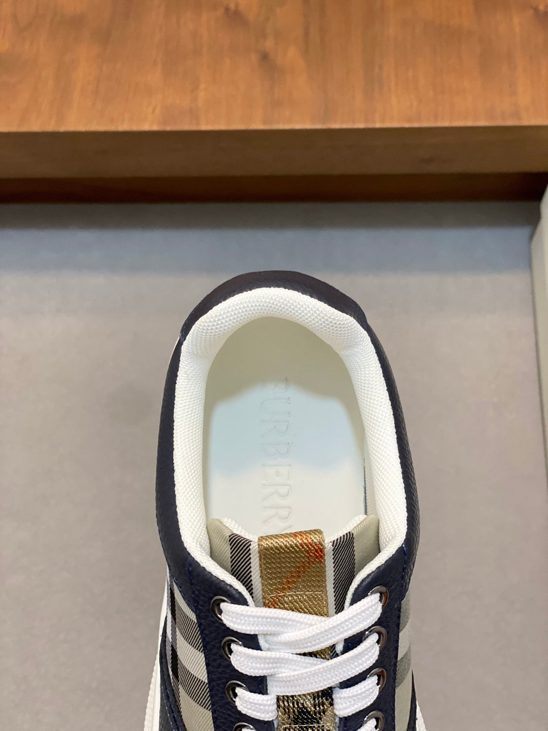 Navy sneaker tongue and lace area with white lining and woven tag detail