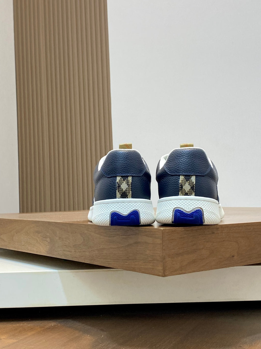 Back view of navy low-top sneakers with check accents and blue-trimmed soles
