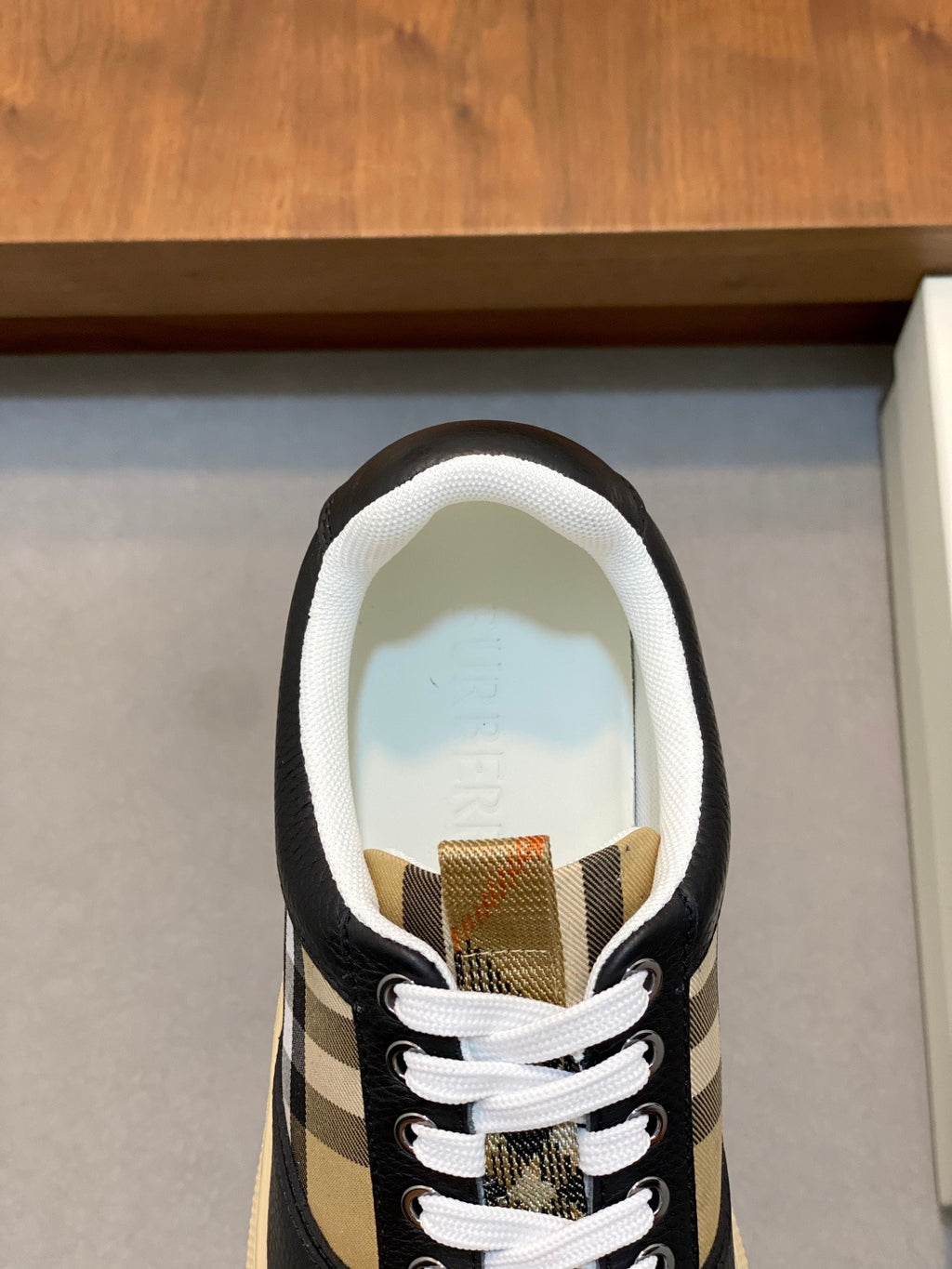 Sneaker close-up with white lining, white laces, and beige-and-black check panel