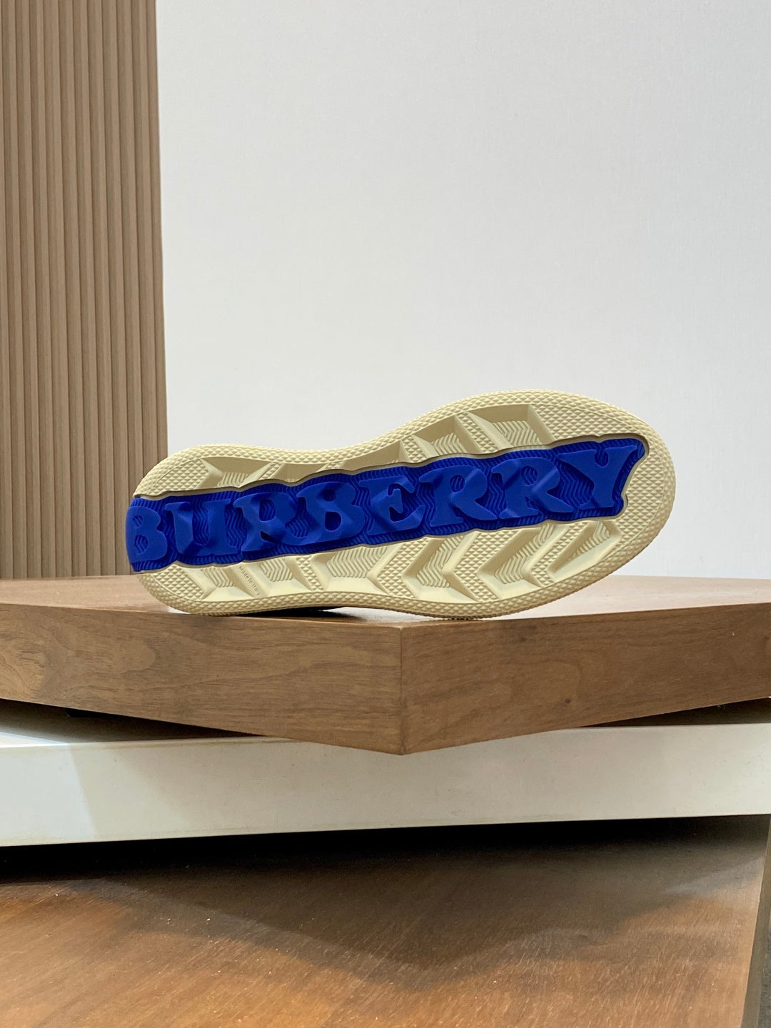 Shoe outsole with blue embossed lettering and beige rubber tread