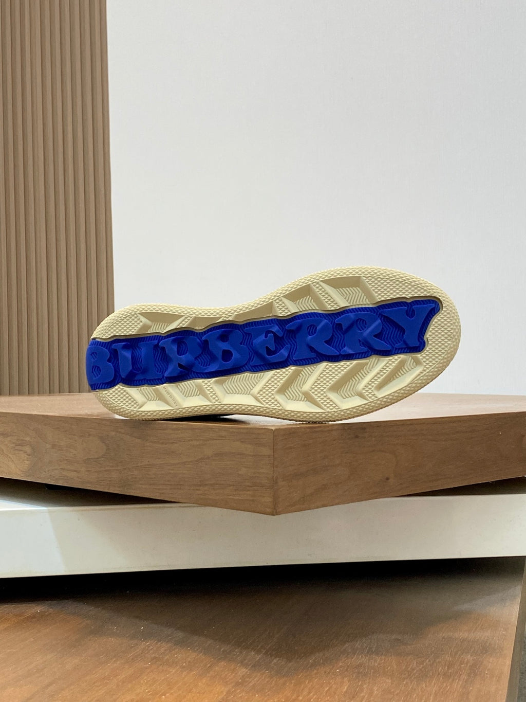 Outsole view of low-top sneakers with blue tread pattern on beige rubber sole