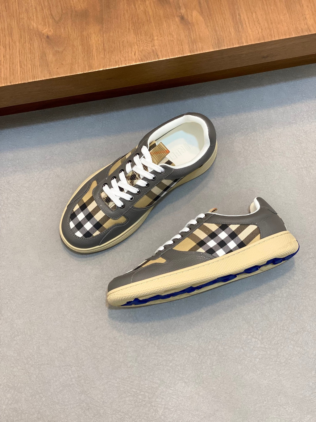 Burberry sneakers with black-and-tan check quarter panels, white laces, and beige sole
