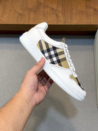 Burberry low-top sneaker, white leather and check side panel, held in hand
