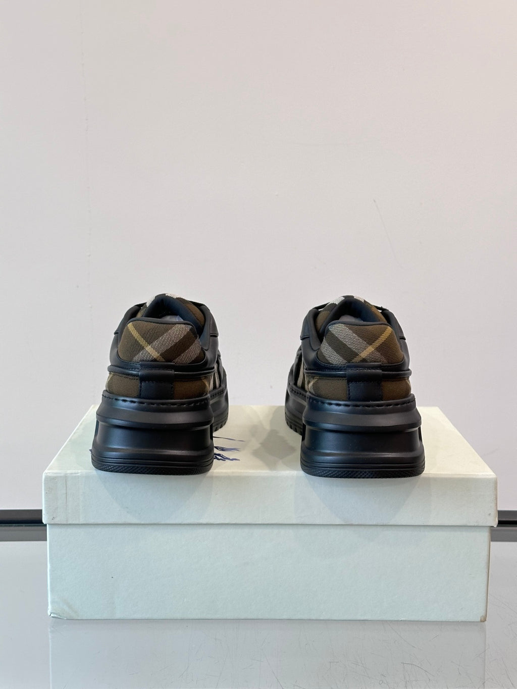 Heel view of dark navy lace-up sneakers with beige plaid stripe detail