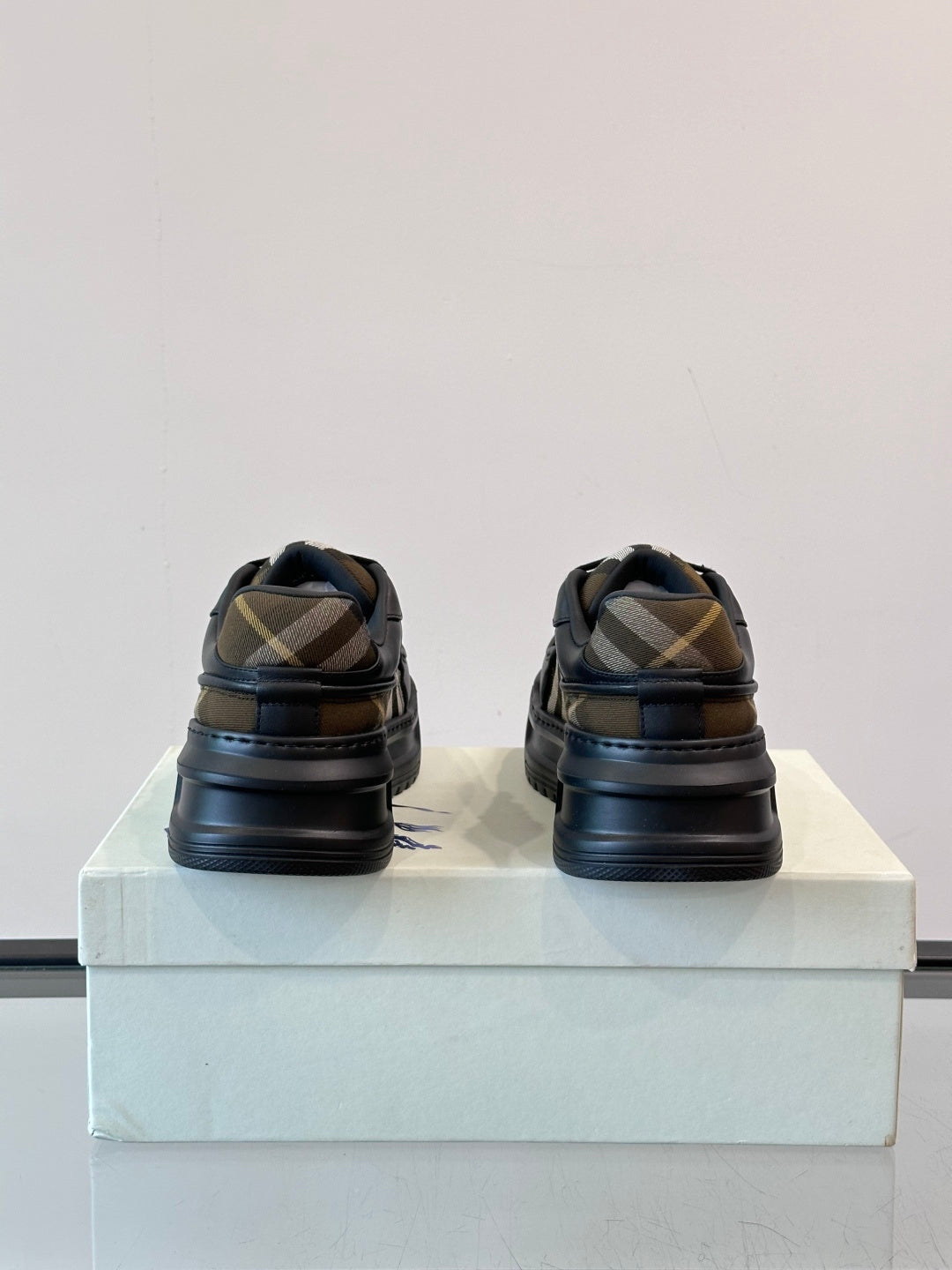 Heel view of dark navy lace-up sneakers with beige plaid stripe detail