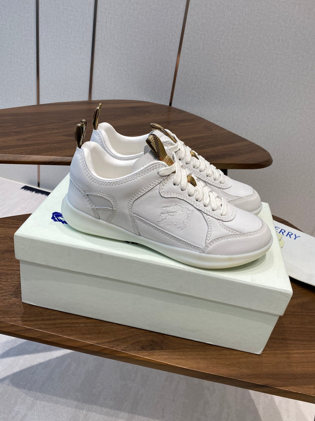 Burberry white leather sneakers, side view, gold-tone heel detail and lace-up