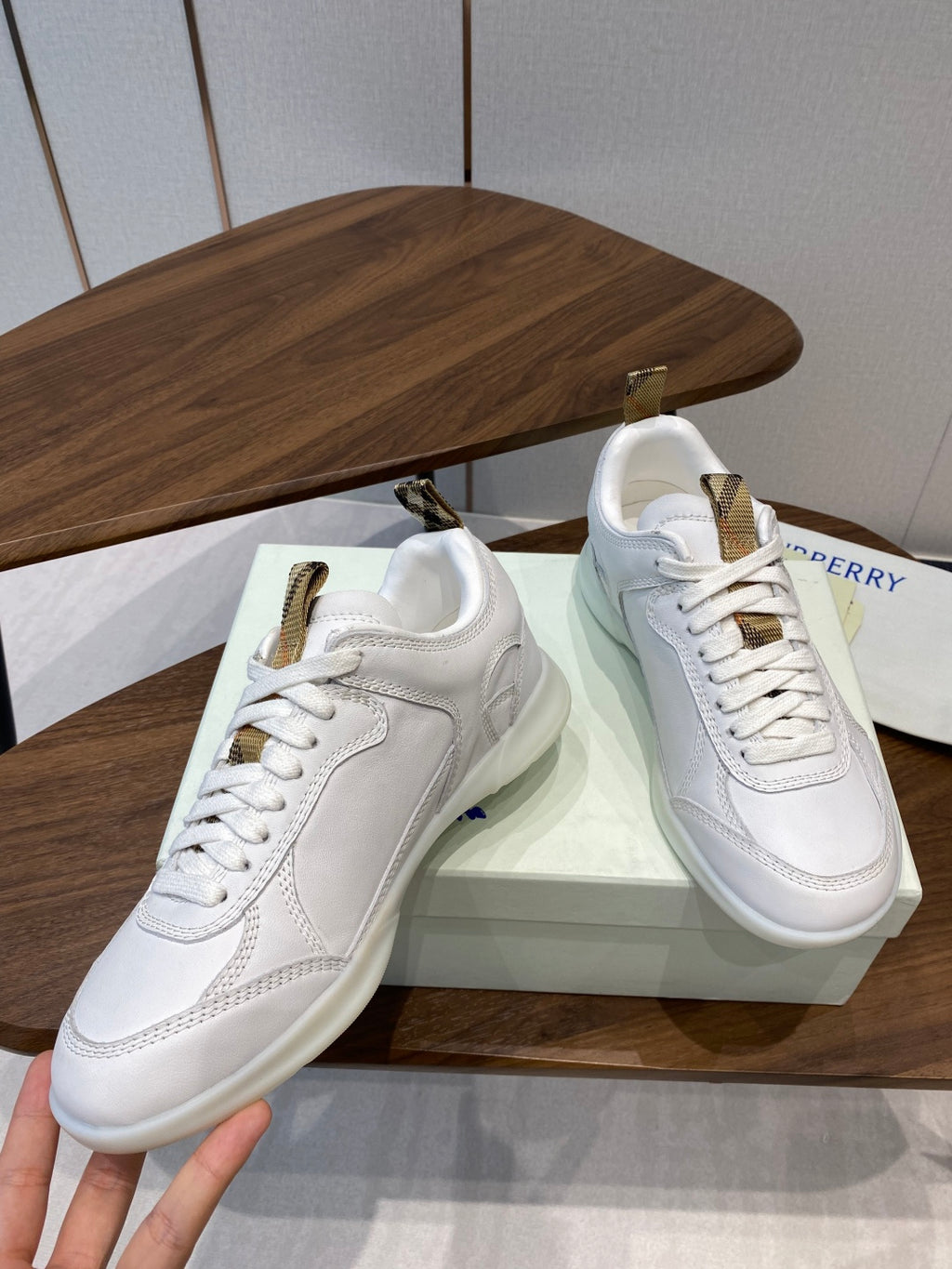 Burberry white leather sneakers, front view, gold-tone lace hardware and tongue tag