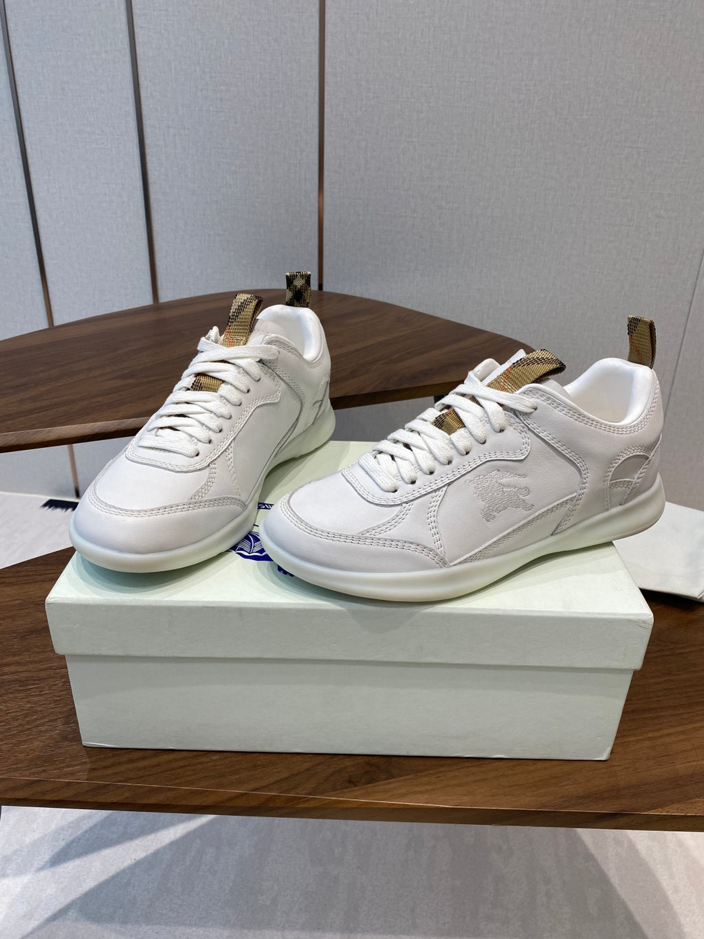 Burberry white leather sneakers, angled view, lace-up and gold-tone heel tabs