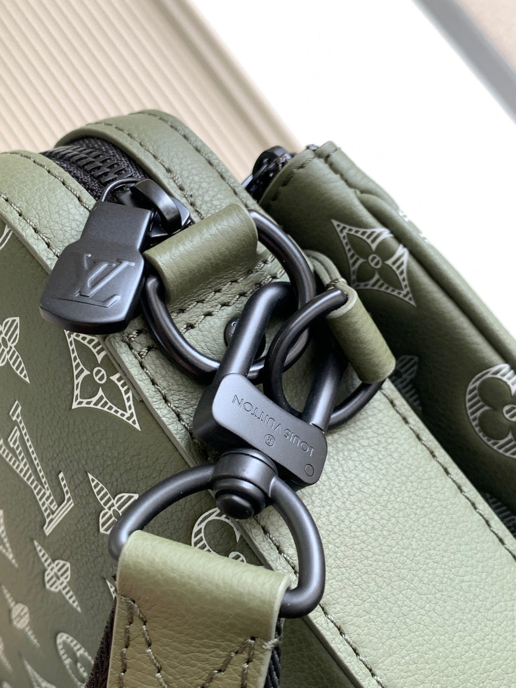 Olive green bag with black metal D-rings and clasp hardware on the strap