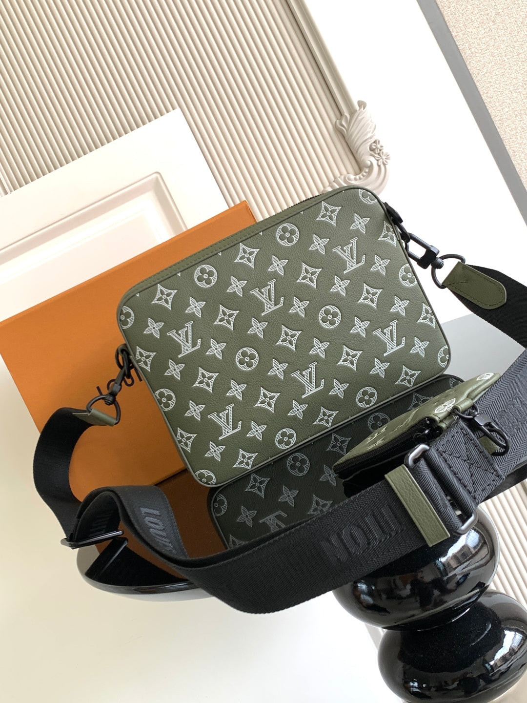 Olive green crossbody bag with white monogram pattern, side strap and zip pocket