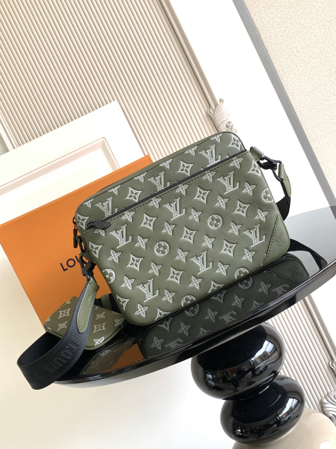 Olive green crossbody bag with white monogram pattern and top flap, black strap