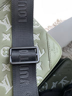 Olive green bag with dark patterned shoulder strap and rectangular metal buckle