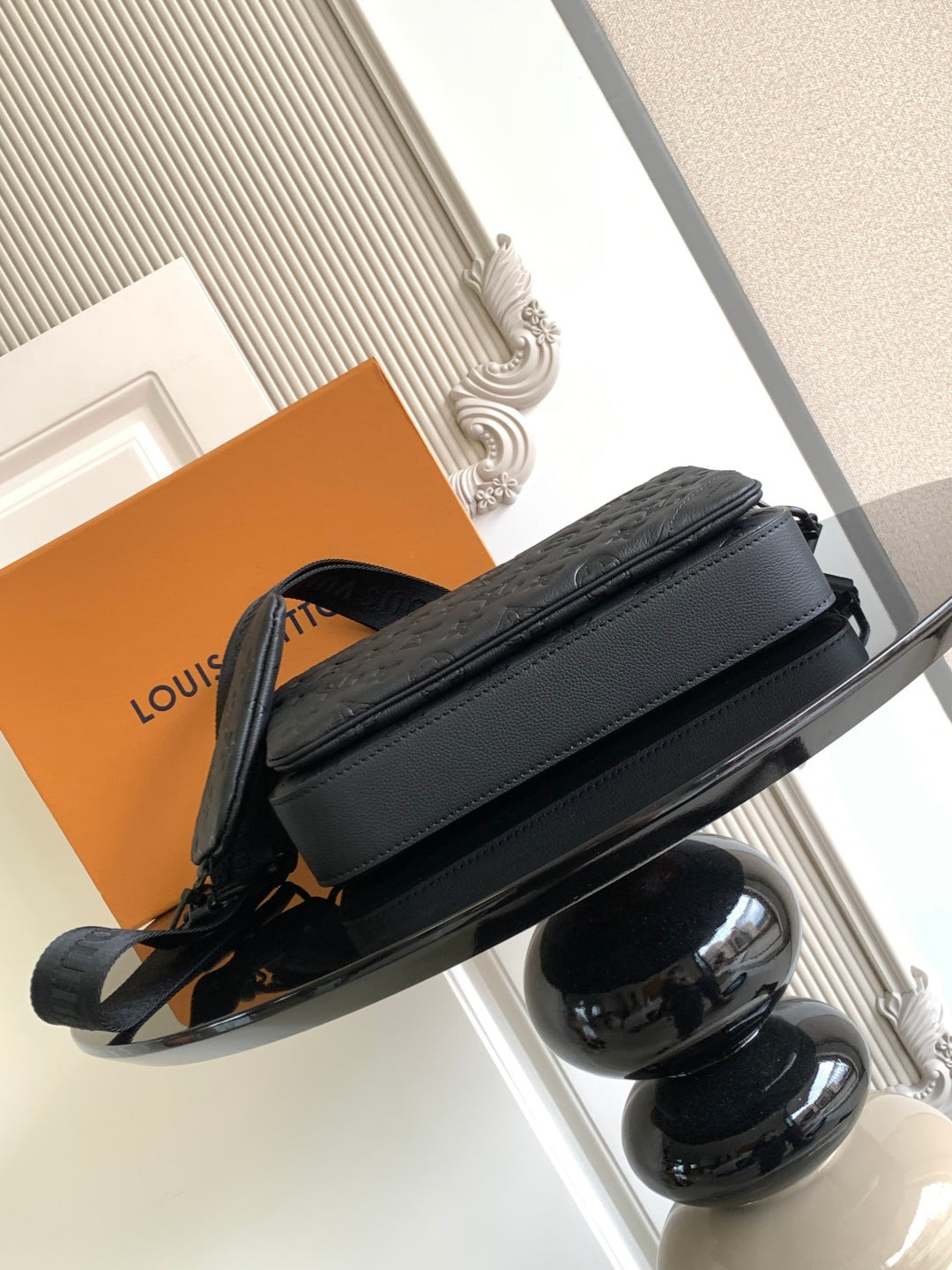 Small structured crossbody bag with single strap, dark leather, front flap.