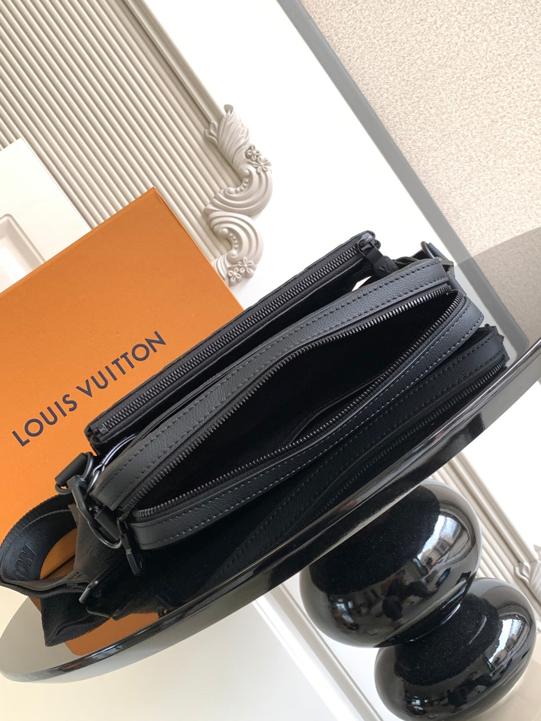 Zip-top crossbody bag with multiple compartments, dark leather and logo charm.